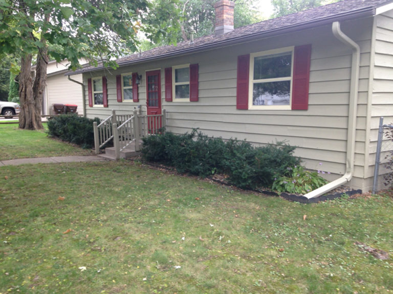 Freshly painted tan house with maroon shutters and front door